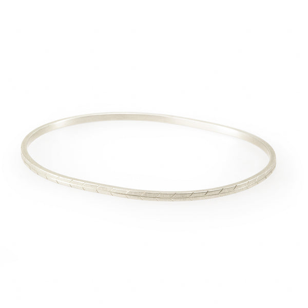 A narrow oval bangle hand-etched with a grassland motif. Made by artisan hands in ethically mined sterling silver in Cape Town.