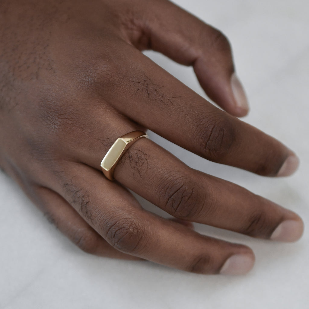 Eco-conscious signet ring in yellow 9K gold on man's hand, handmade and ethical.
