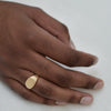 A square 9K gold signet ring worn on a man’s finger.