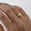 A square 9K gold signet ring worn on a woman’s finger.