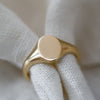 Dainty yellow gold oval signet ring, sustainably handcrafted jewelry piece.