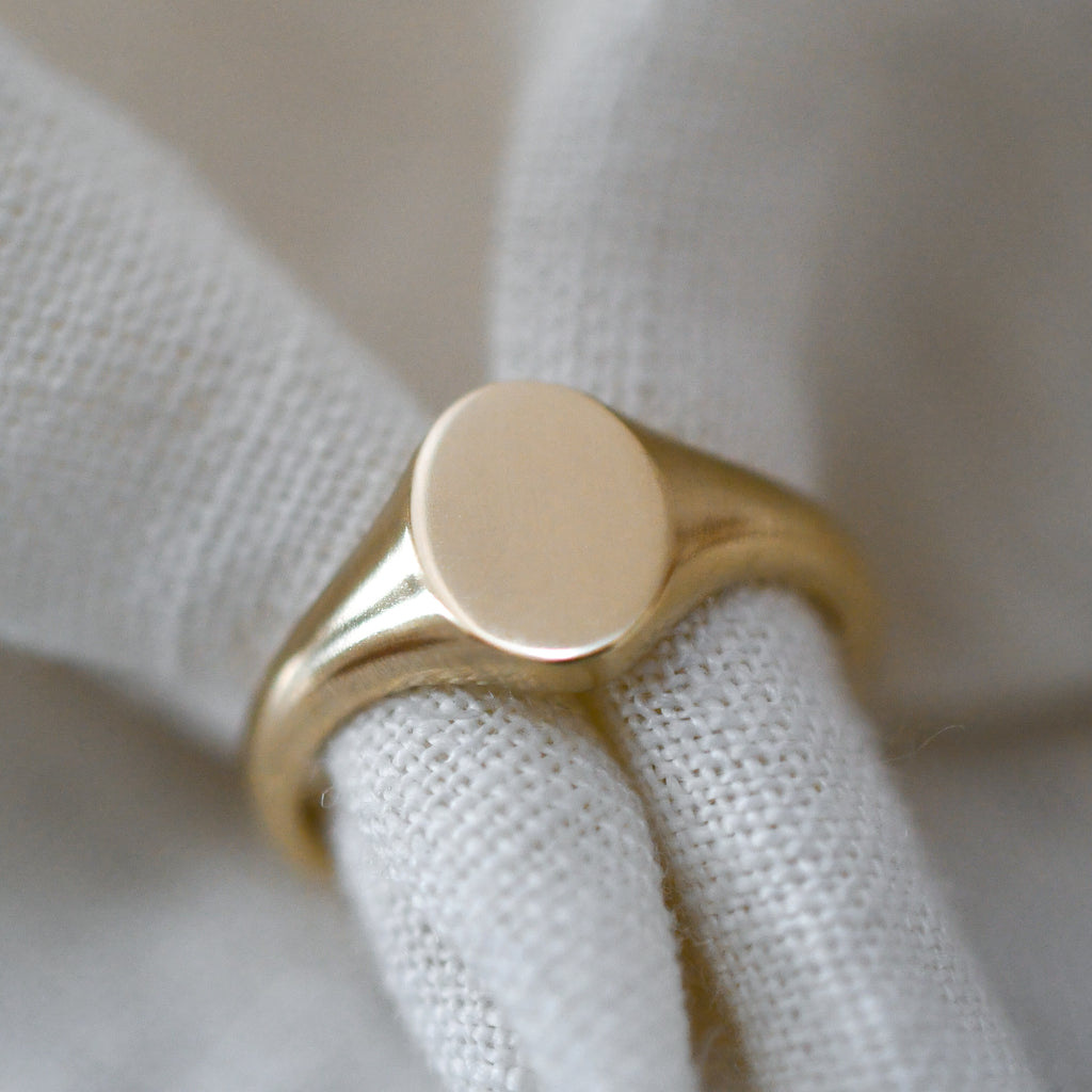 Dainty yellow gold oval signet ring, sustainably handcrafted jewelry piece.