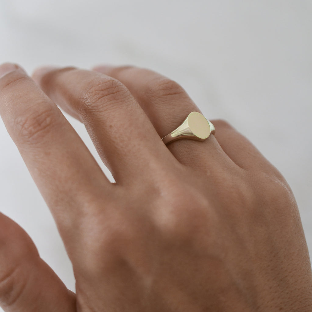 Dainty ethical gold oval signet ring handcrafted from Fairmined eco-friendly gold on woman's hand