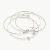 An interconnected set of 4 narrow sterling silver bangles with free-hanging oval charms. Made in Cape Town with high-quality craftsmanship for 15 years.