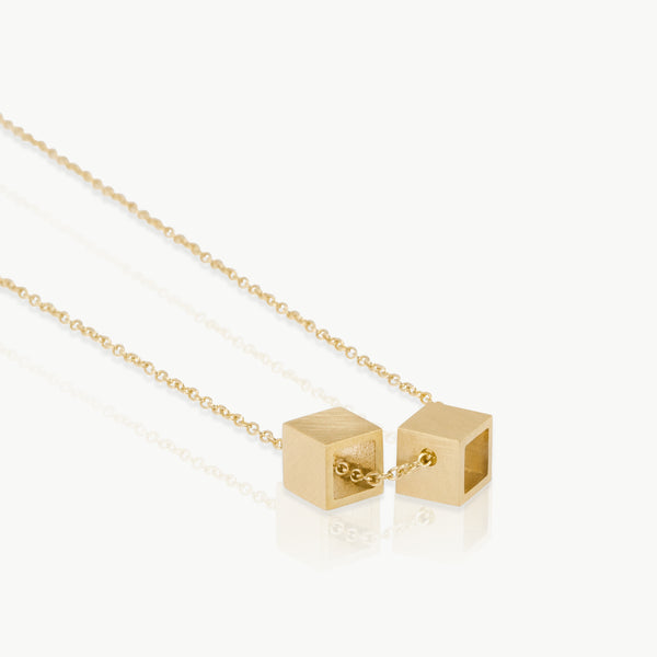 2 open cubes threaded on a chain, this minimalist geometric necklace is handmade in the Old Biscuit Mill, Cape Town in Fairmined 9K solid gold. 