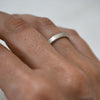 Close-up of a hand wearing a silver ring on a plain background