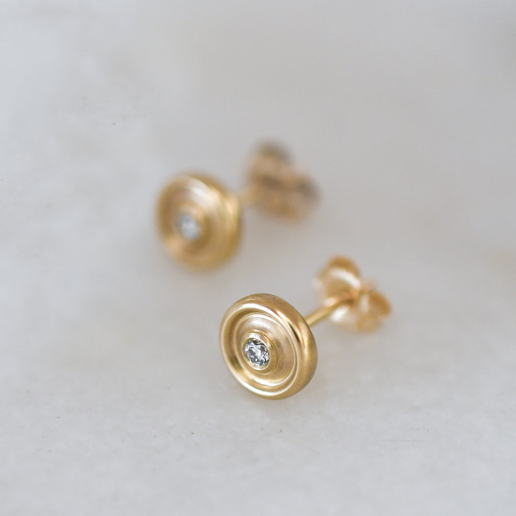 Fairmined certified gold earrings with a central lab-grown diamond on a light gray background