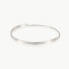 Minimalist silver Flow bangle crafted in Fairmined metal with soft fluid curves.