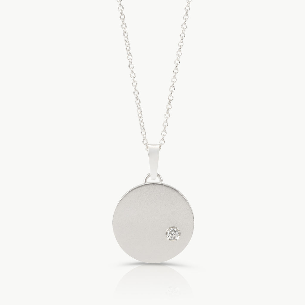 Handcrafted by an independent jeweller in Cape Town – A large disc pendant in sterling silver and set with a lab-grown diamond, inspired by the night sky. 