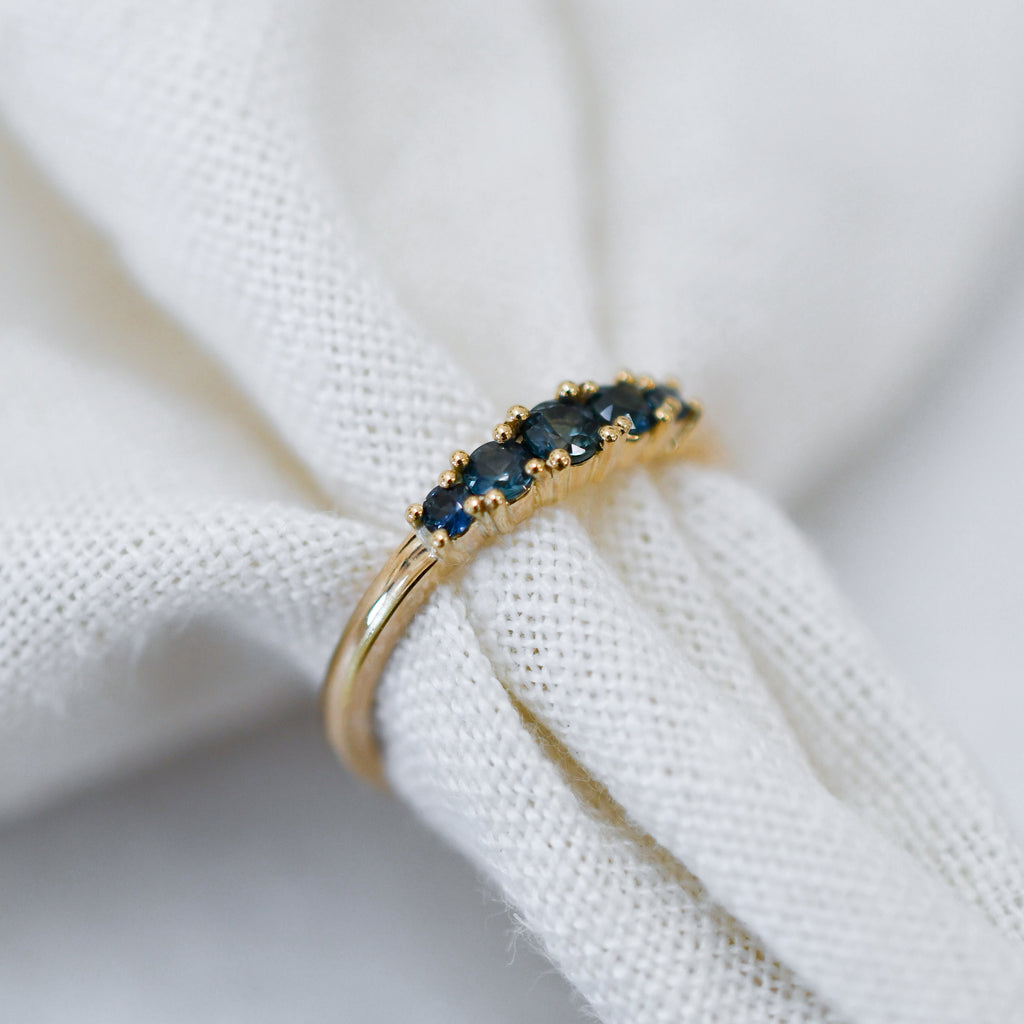 Sustainable jewellery — yellow gold ring featuring a row of blue sapphires