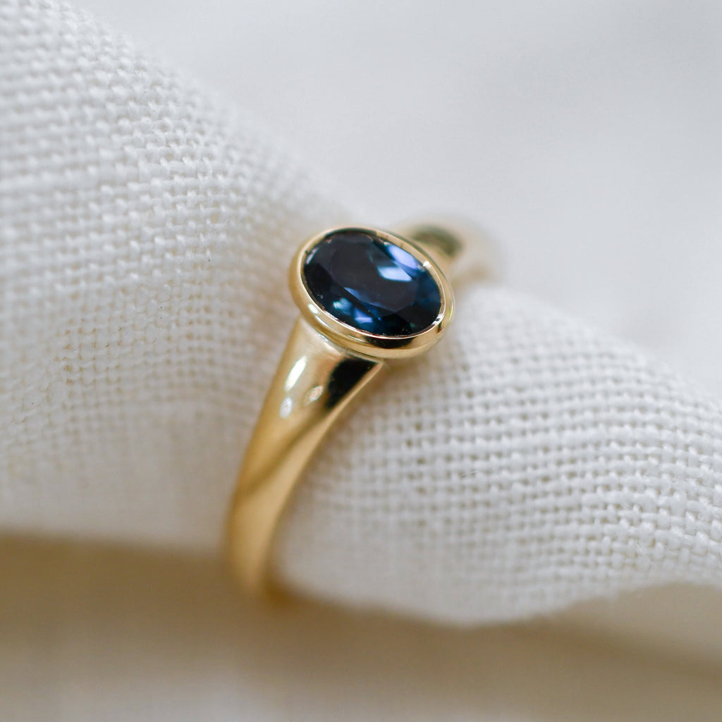 Sustainable jewellery — yellow gold ring with one deep blue sapphire and tapered band
