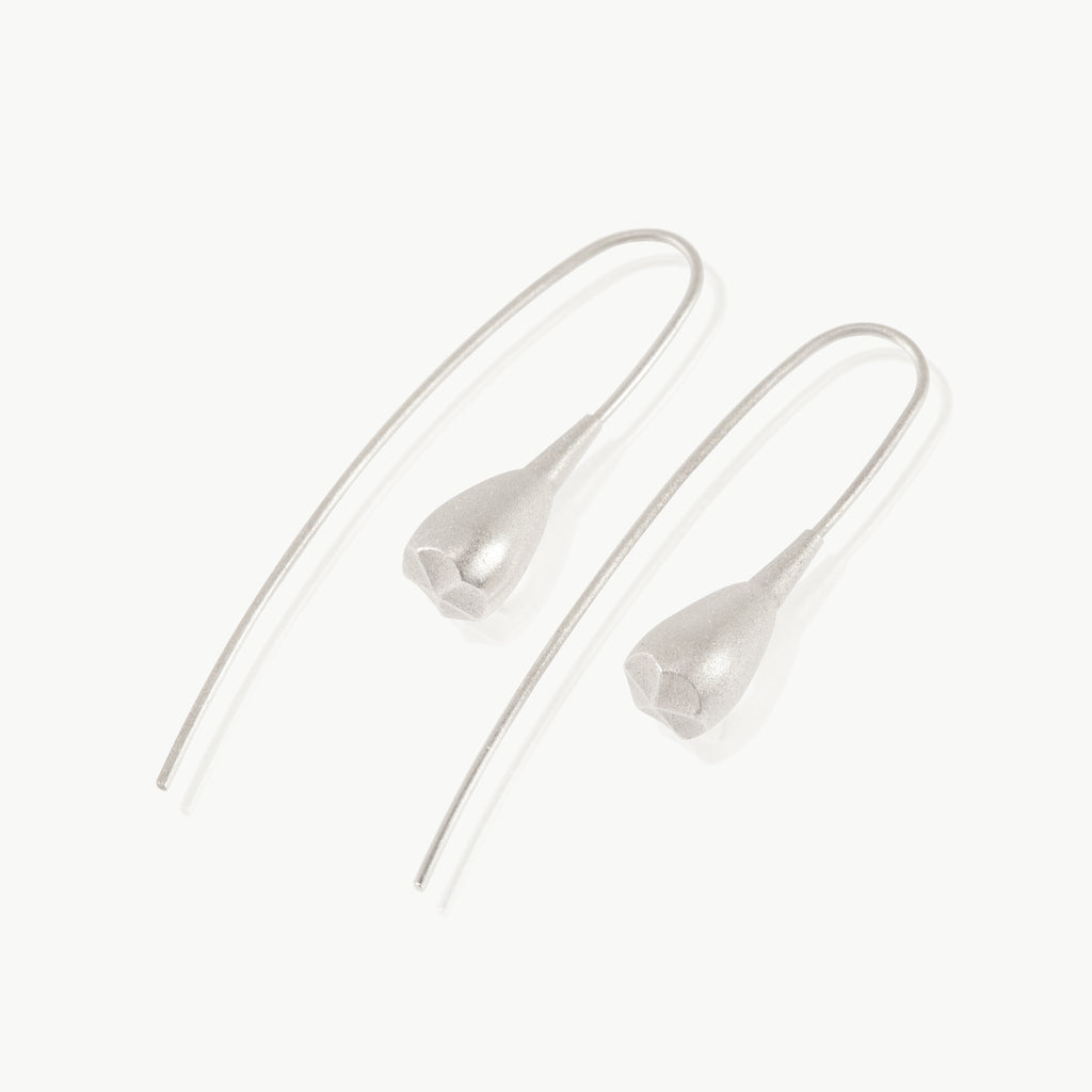 A minimalist seed pod hanging at the end of a wire drop earring is botanically inspired and expertly crafted in sterling silver in South Africa.