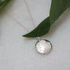 Curved Disc silver pendant featuring a detailed hand-engraved leaf wreath, made from sustainable, Fairmined silver.