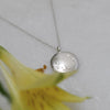 Ethical sterling silver round pendant with soft matte-polished finish and hand-engraved botanical design.