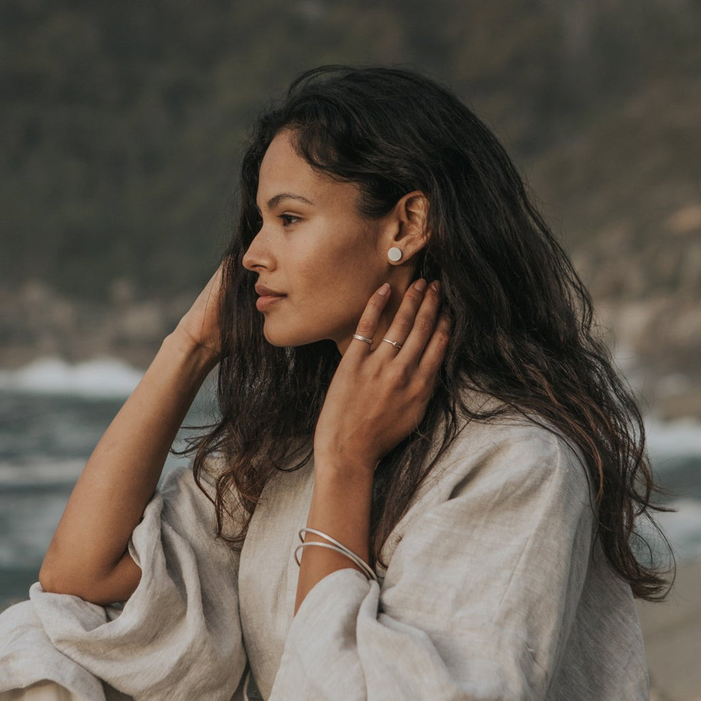 Woman wearing ethical silver earrings. These minimalist 11mm Hemisphere Studs are handmade in Cape Town in recycled silver from e-waste.