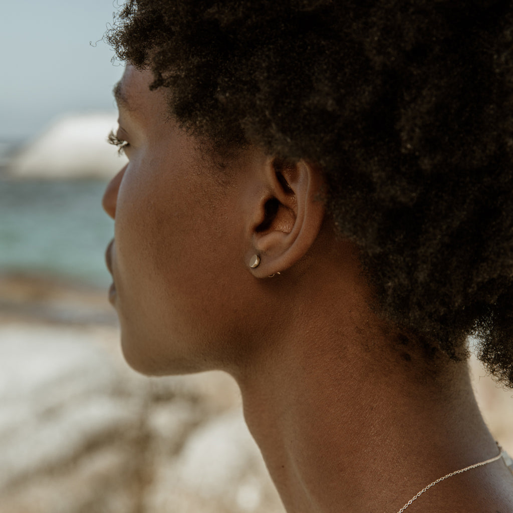 Woman wearing eco-friendly gold earrings. These sustainable 5mm Hemisphere Studs are handmade in Cape Town in recycled gold from e-waste.