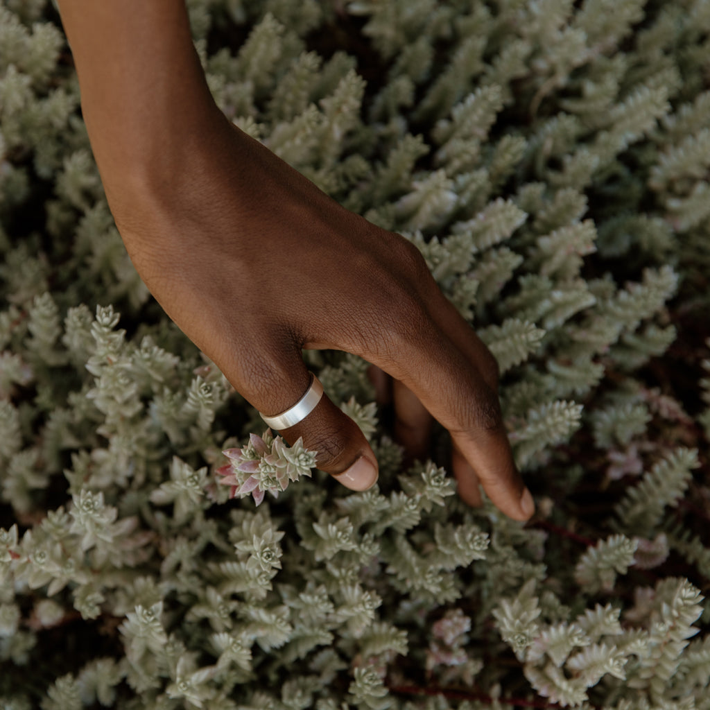 Woman wearing a sustainable silver ring. This artisan Flat Band is handmade in Cape Town in recycled silver from e-waste.