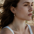 Woman wearing sustainable gold earrings. These ethical Pod Earrings are handmade in Cape Town in recycled gold from e-waste.