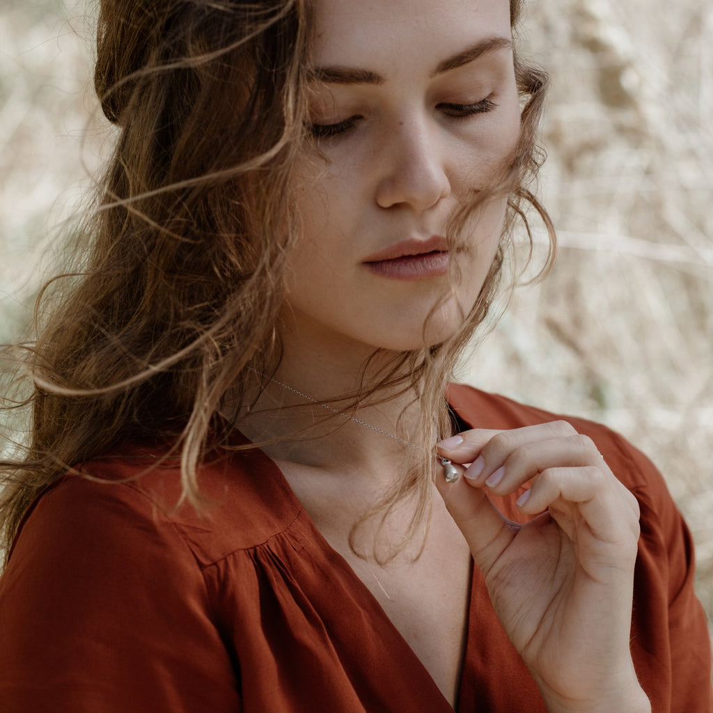 Woman wearing sustainable silver necklace. This artisan crafted Pod Pendant is handmade in Cape Town in recycled silver from e-waste.