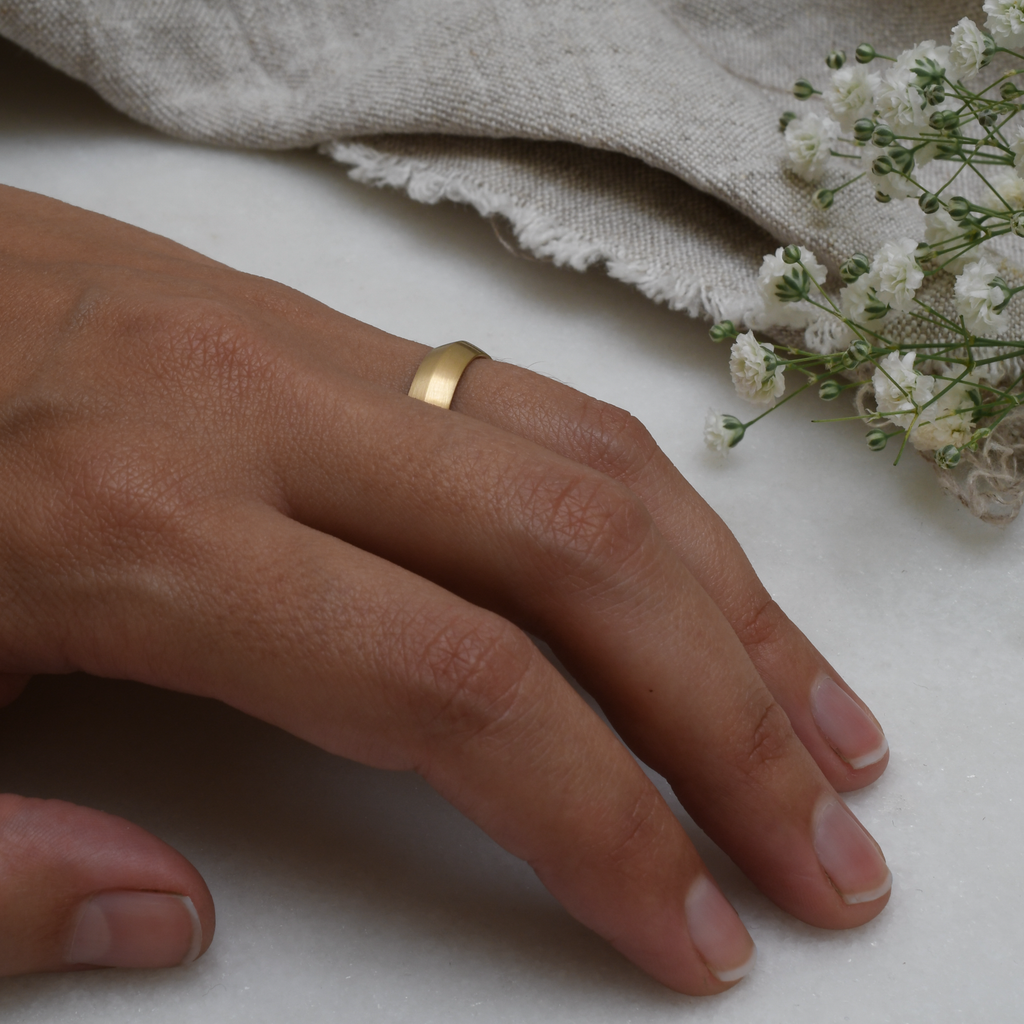 Knife Edge eco-friendly recycled gold wedding band on woman's hand