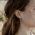 Woman wearing ethical gold earrings. These minimalist Seed Earrings are handmade in Cape Town in recycled gold from e-waste.