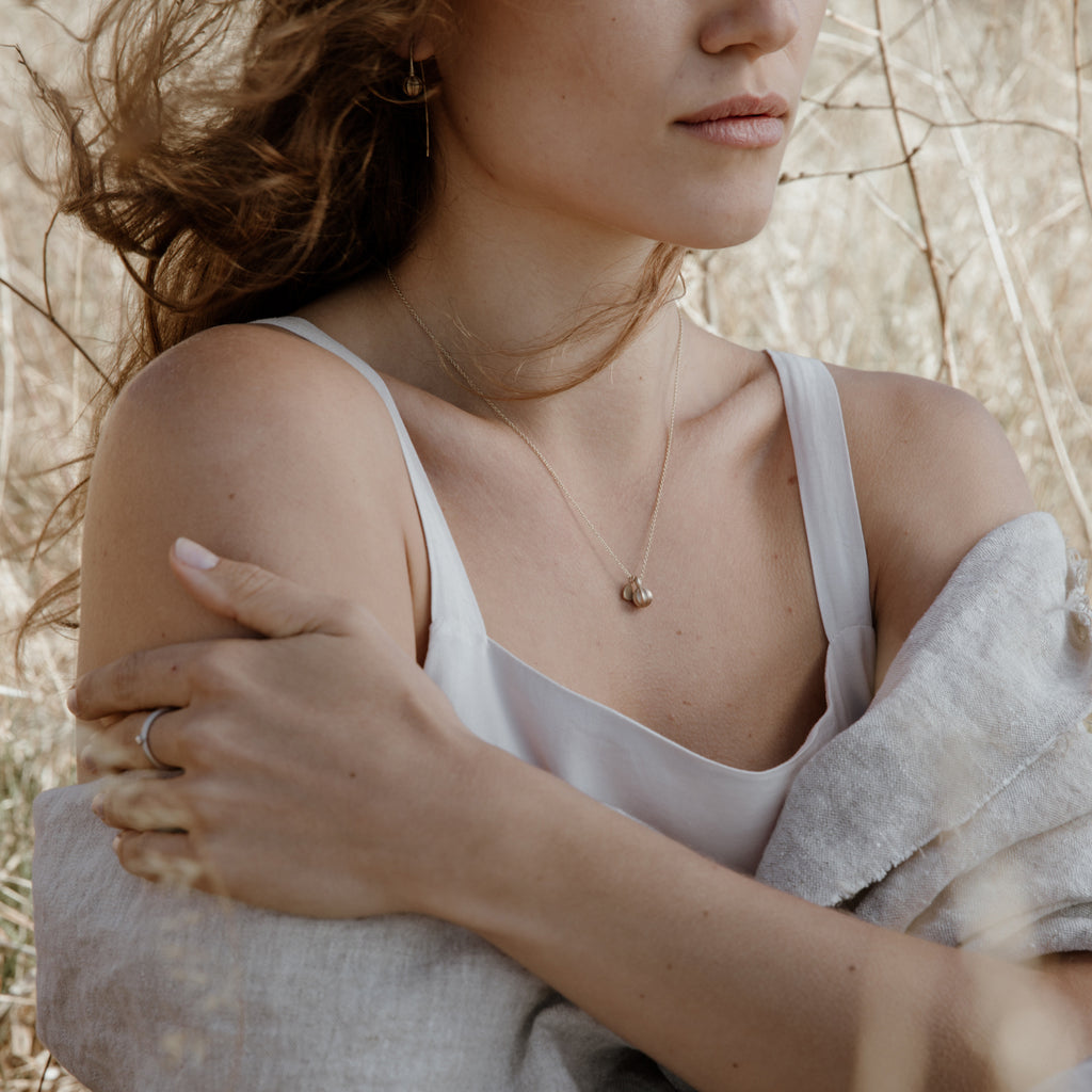 Woman wearing eco-friendly gold necklace. This sustainable Seed Pendant with Leaf is handmade in Cape Town in recycled gold from e-waste.