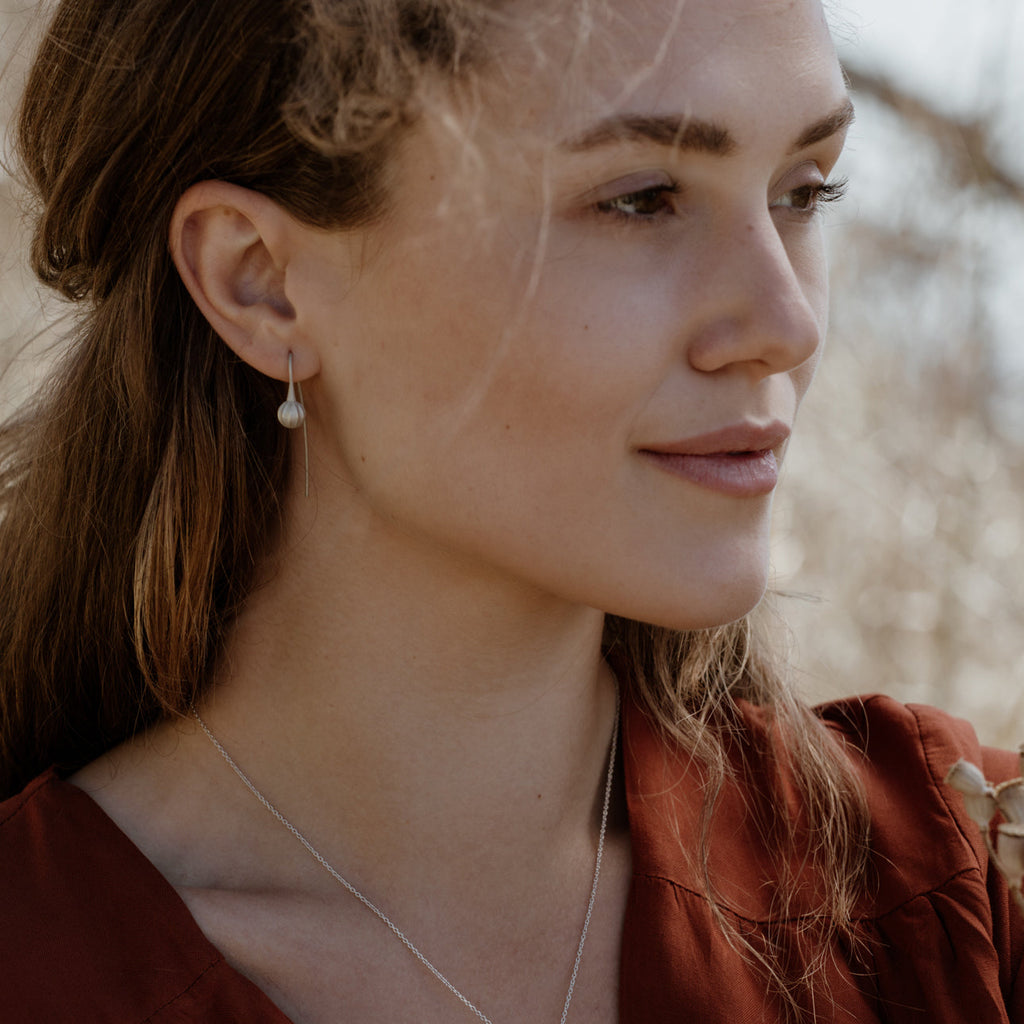 Woman wearing ethical silver earrings. These minimalist Seed Earrings are handmade in Cape Town in recycled silver from e-waste.