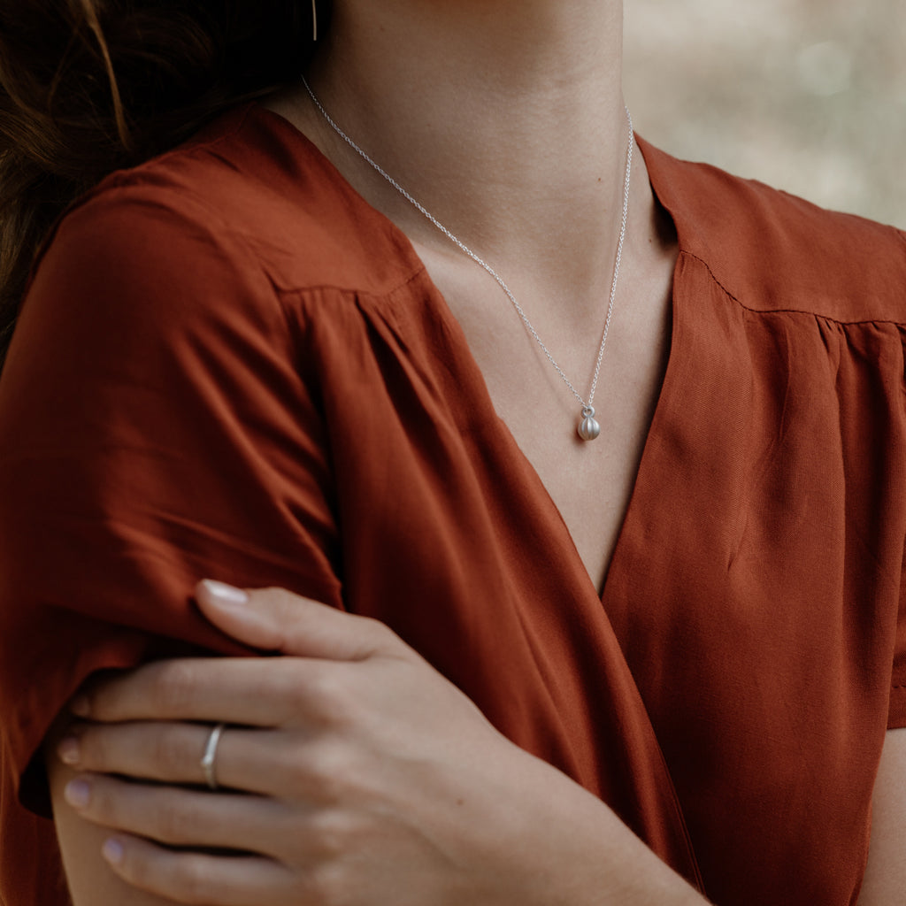 Woman wearing ethical silver necklace. This minimalist Seed Pendant is handmade in Cape Town in recycled silver from e-waste.