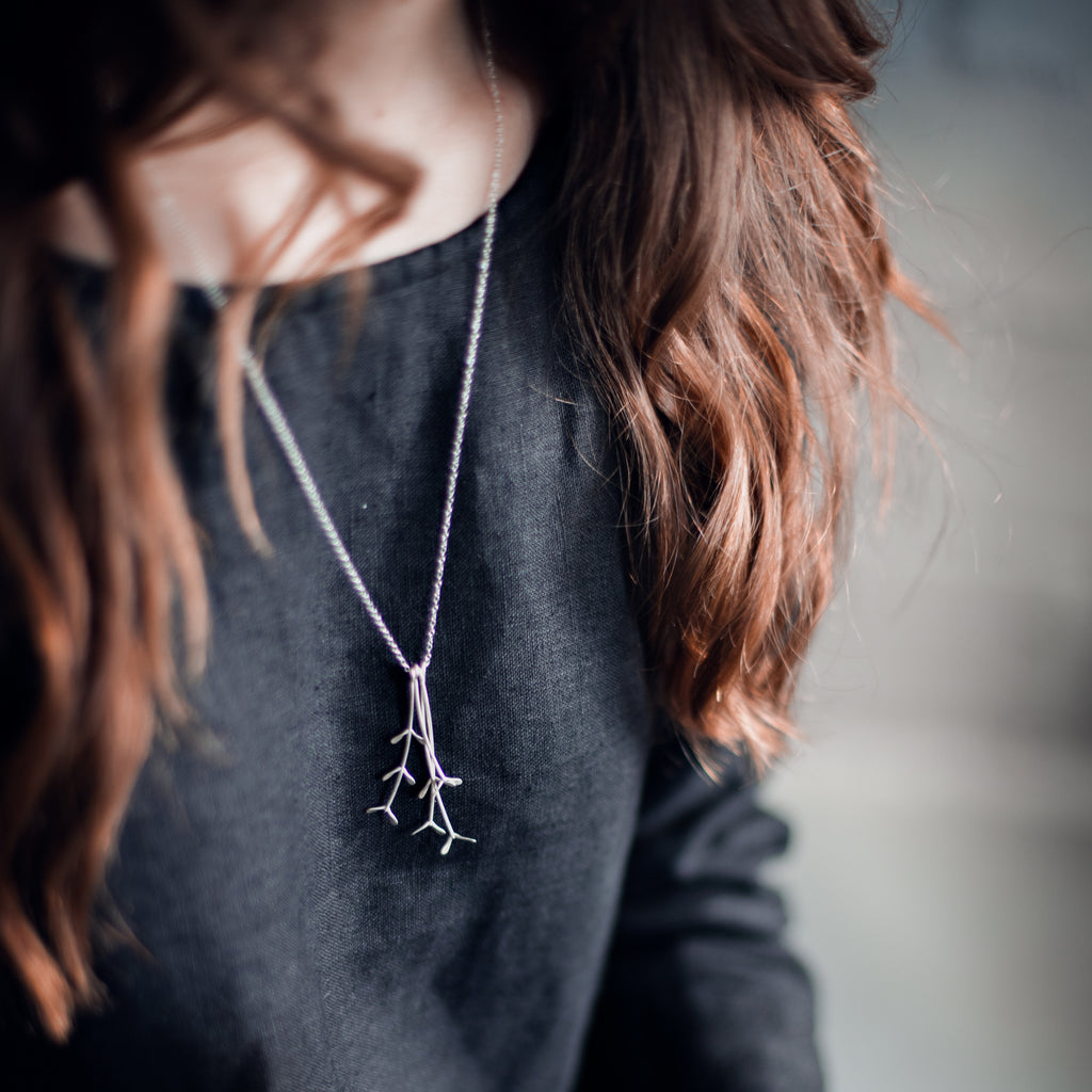 Woman wearing a sustainable silver pendant. This artisan crafted Grassveld Pendant is handmade in Cape Town in recycled silver from e-waste.