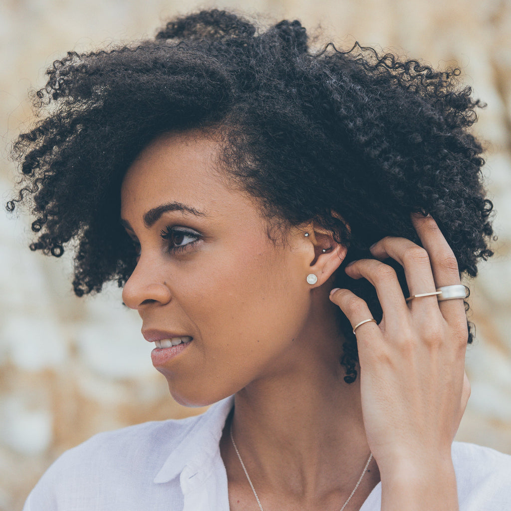 Woman wearing ethical silver earrings. These eco-friendly Vessel Studs are handmade in Cape Town in recycled silver from e-waste.